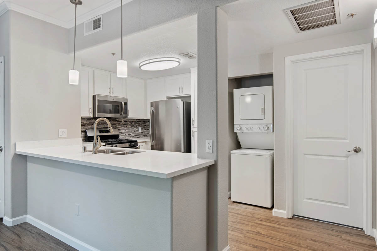 Kitchen area with dual washer and dryer combo with white walls at the Terraces at Highland development