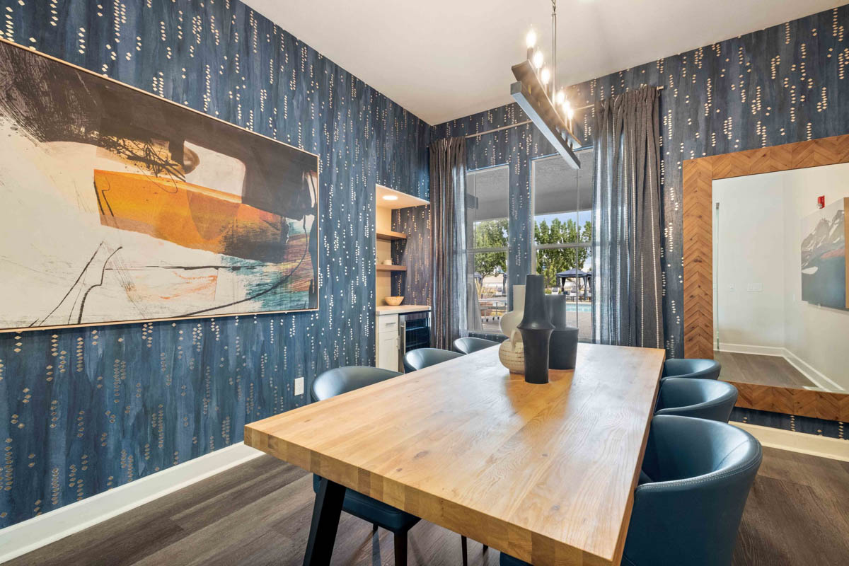 Dining room area with solid wood table, blue chair, and minimalist artwork at the Terraces at Highland development