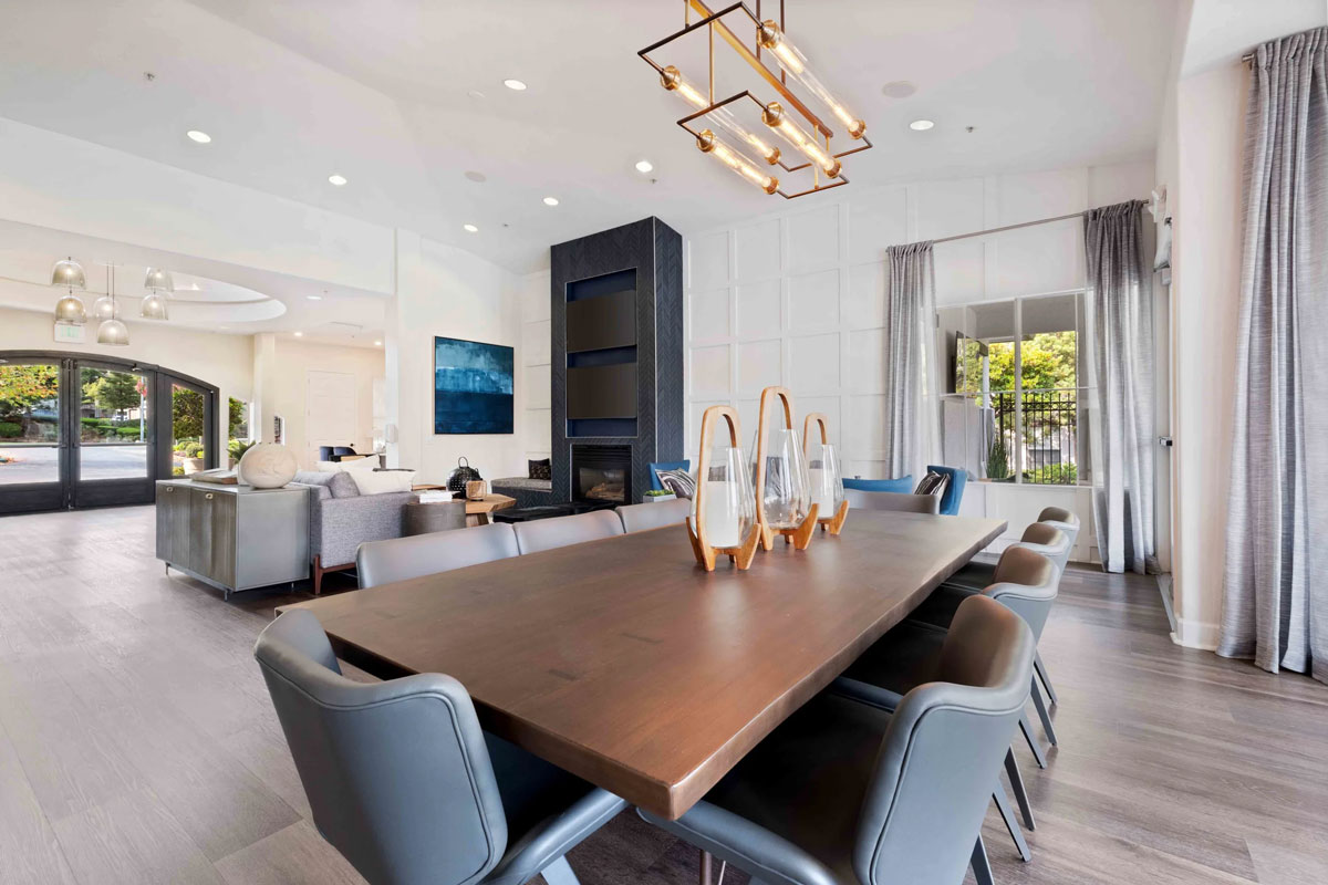 Dining room table and chairs overlooking the living room with modern light elements and large drapes at the Terraces at Highland development